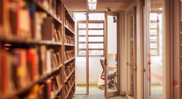 A spacious library interior featuring tall shelves filled with a variety of books.